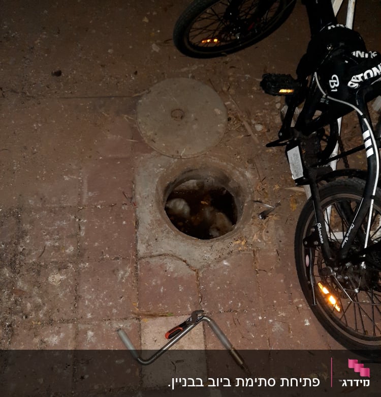 פתח ביוב פתוח עם כלי עבודה על הקרקע